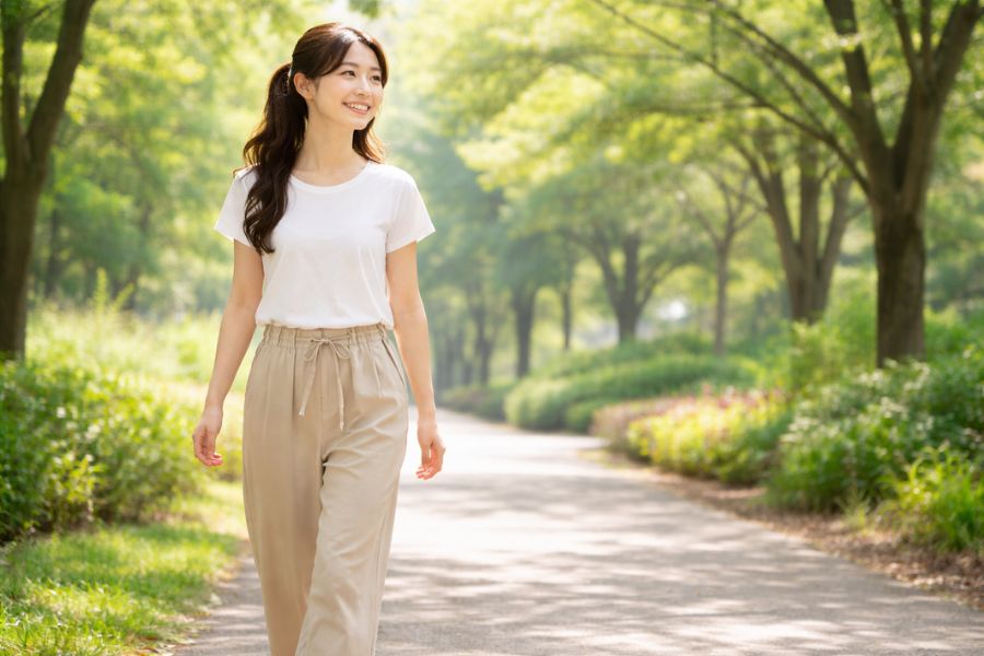 緑あふれる公園を散歩する健康的な印象の女性