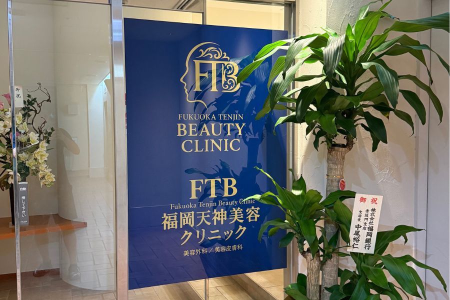 クリニックの受付カウンターで笑顔で立つ制服姿のスタッフ