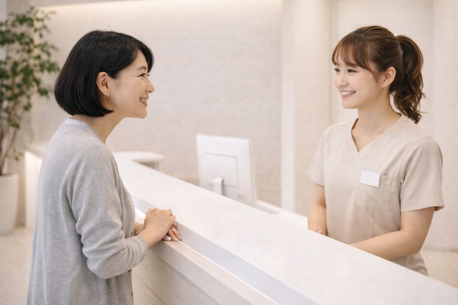 受付カウンター越しに制服スタッフと話している女性患者