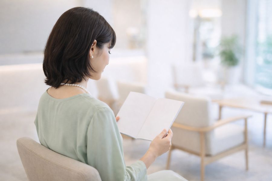 待合エリアで資料を読む女性の斜め後ろ姿