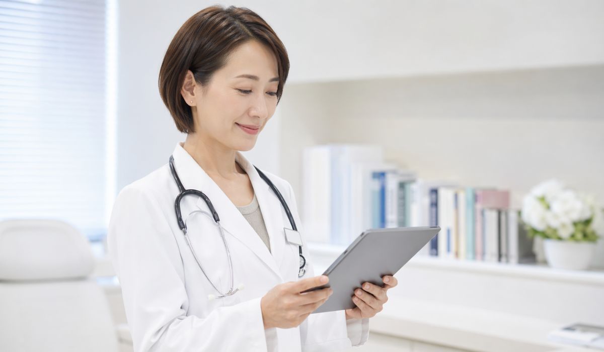 白衣姿でタブレットを確認する女性医師