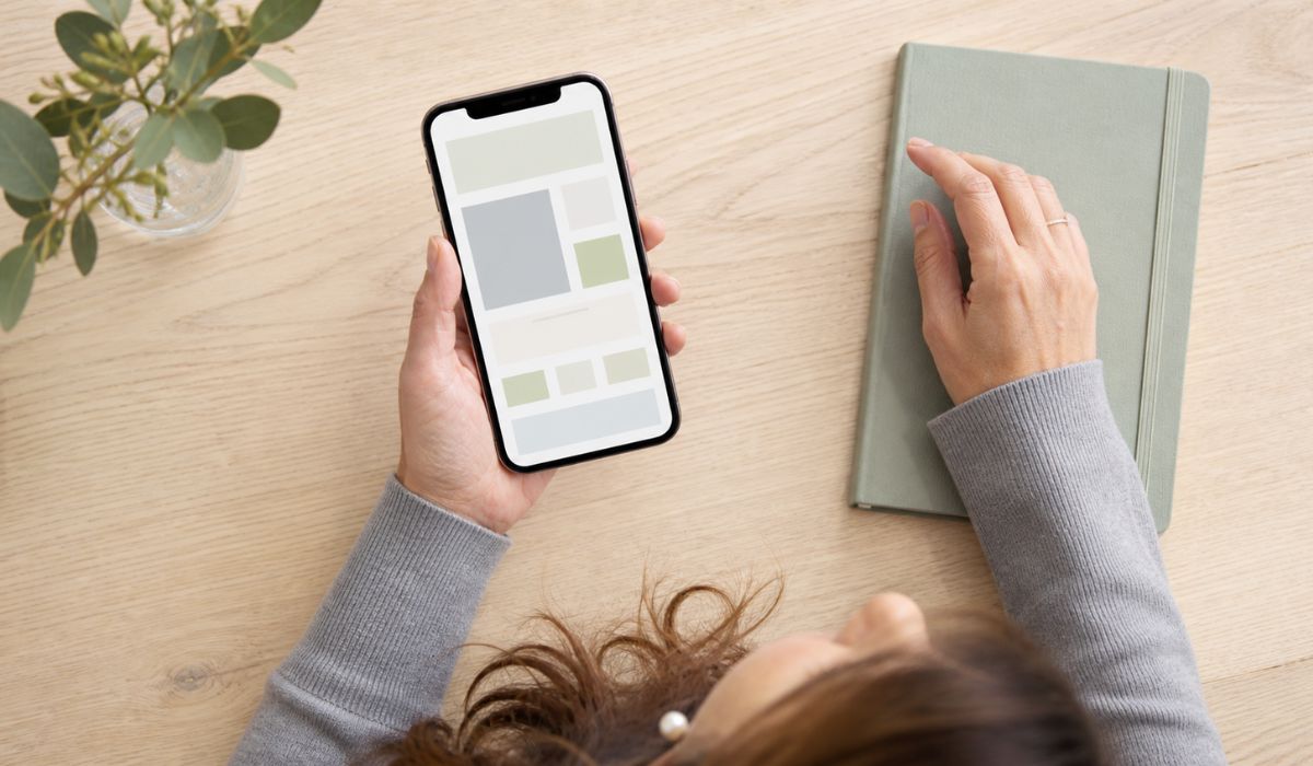 木製テーブル上でスマートフォンを操作する女性の手元（俯瞰）