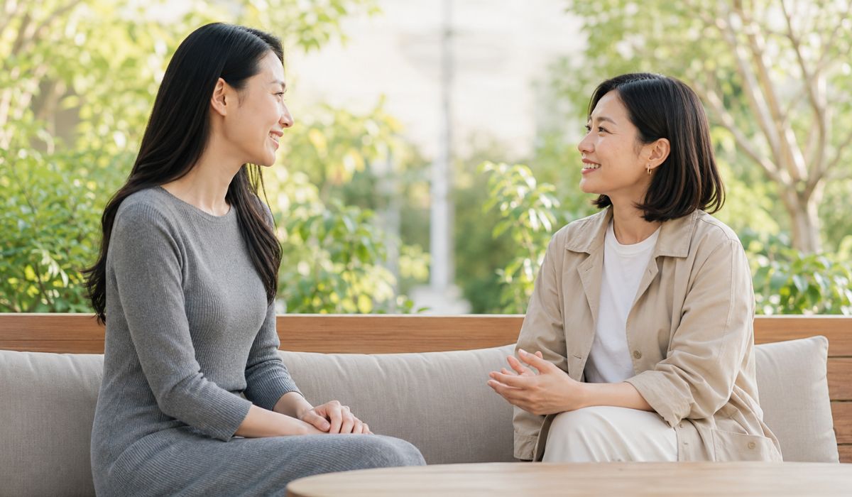 カフェのテラス席で並んで会話する30代後半と40代前半の日本人女性二人