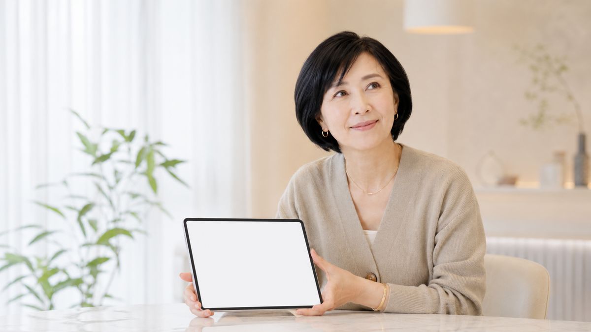 テーブルでタブレットを見て顔を上げる笑顔の女性
