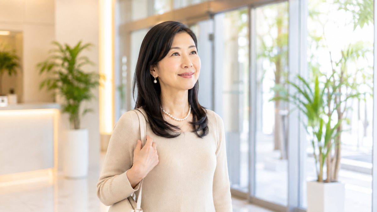 クリニックの入口に立ち、前を見て微笑む女性