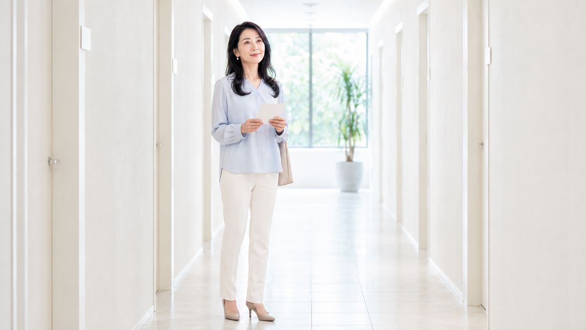クリニックの廊下で立ち止まりメモを確認する女性