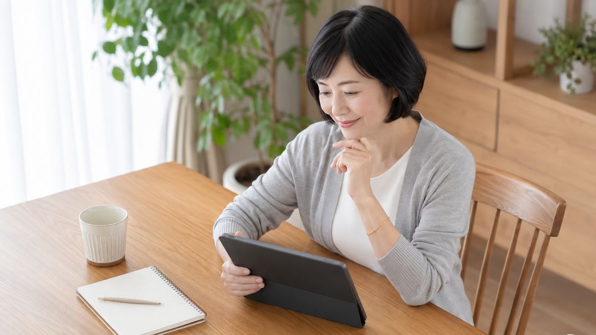 ダイニングテーブルでタブレットを見比べている女性