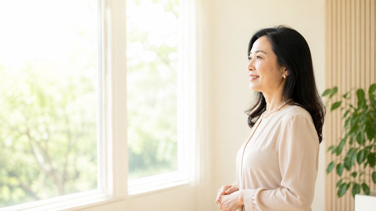 窓辺で外を眺めて微笑む女性の横顔