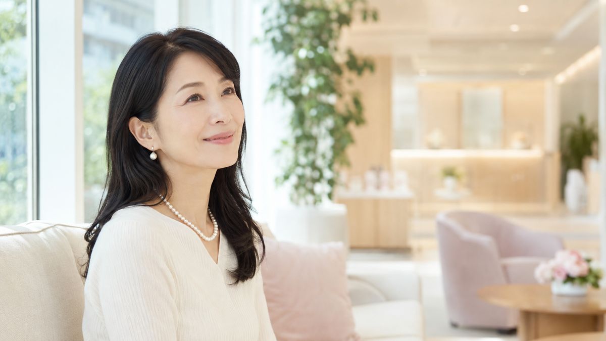 窓際のソファに座って微笑む女性