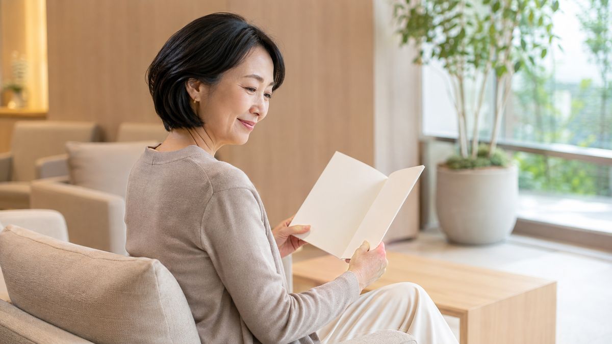 ラウンジのソファに座って冊子を読む女性