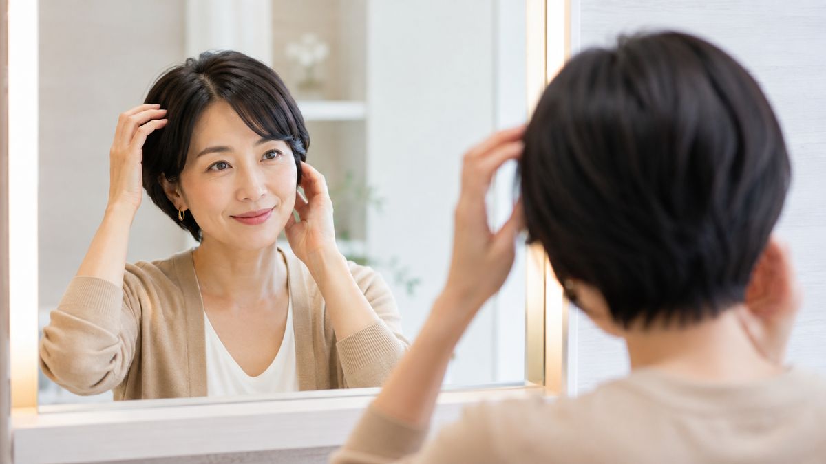 鏡の前で髪に手をあてる女性