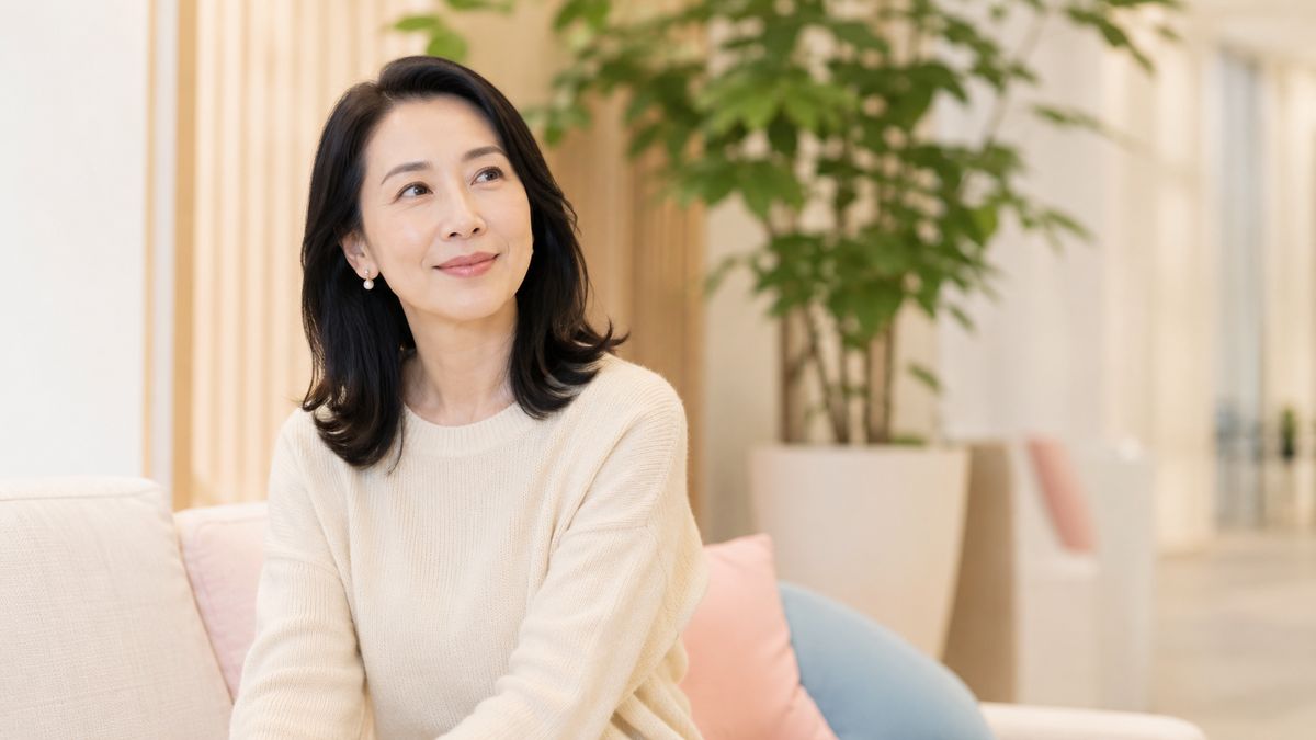 待合ラウンジのソファに腰かけて微笑む女性