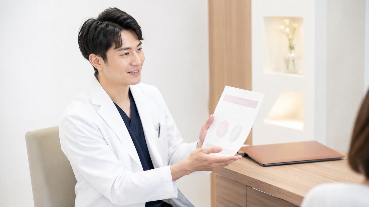 診察室で資料を手に説明している白衣の男性医師