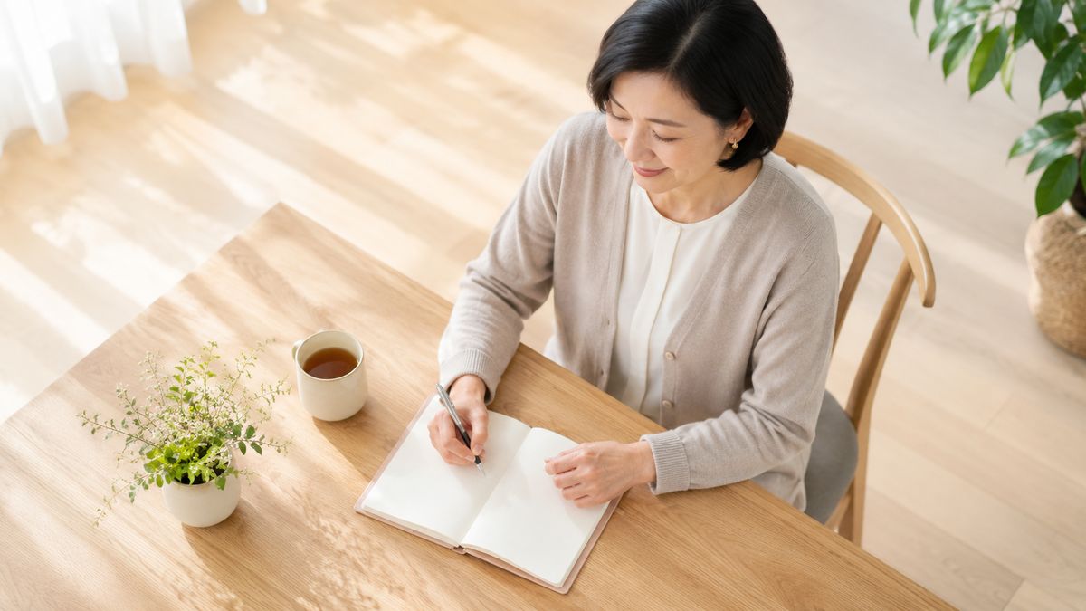 朝のダイニングテーブルで手帳に書き込む女性