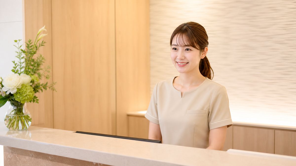 受付カウンターに立つクリニック制服のスタッフ