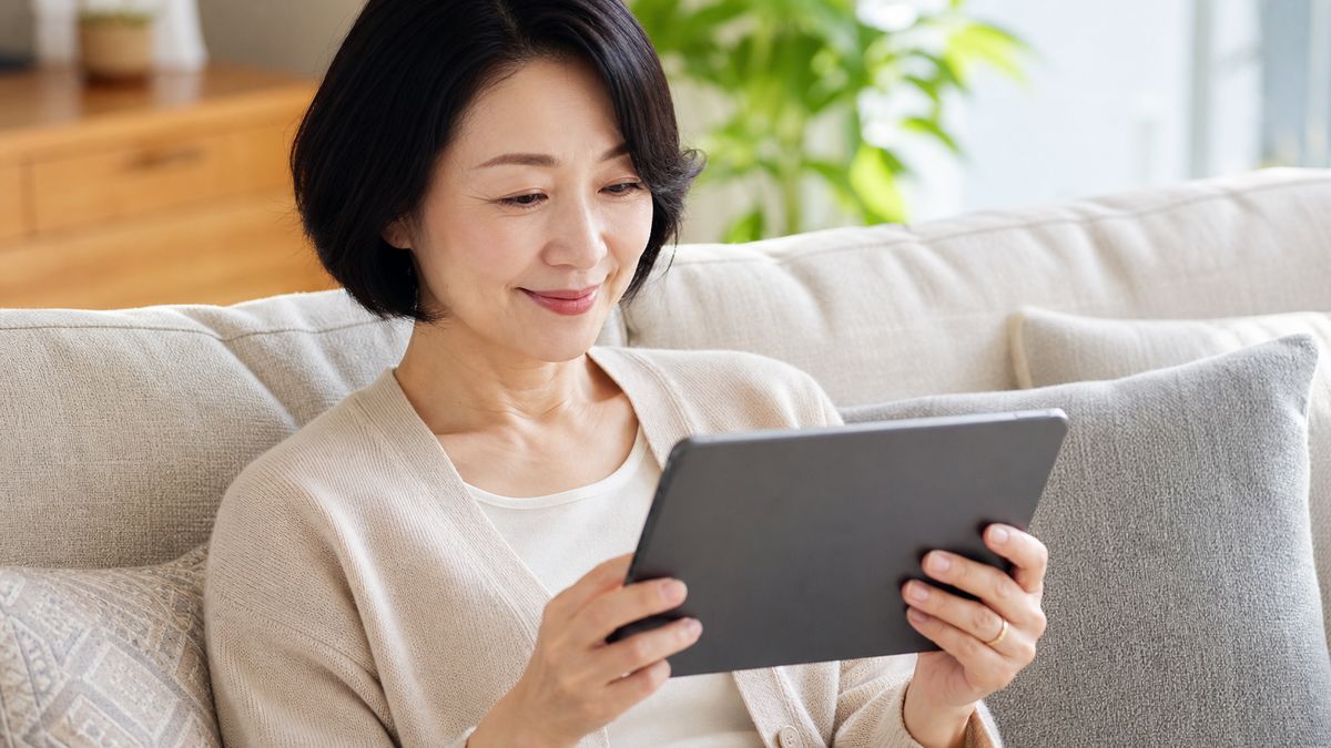 自宅のソファでタブレットを見る女性