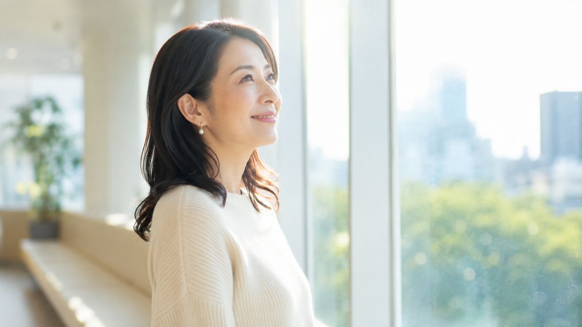 院内の窓辺に立って外を見る女性