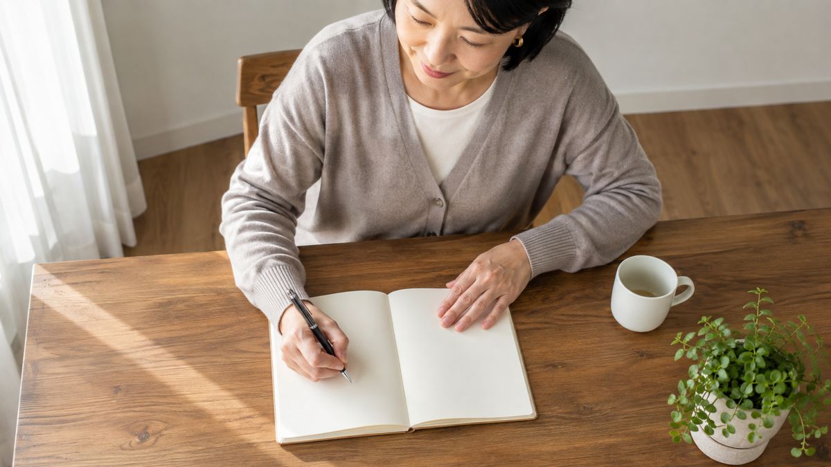 ダイニングテーブルで手帳に書き込む女性