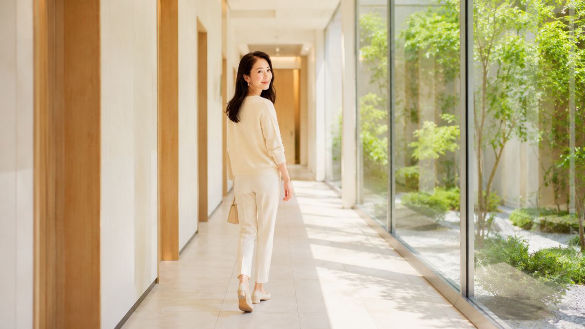 中庭に面した明るい院内通路を歩く女性