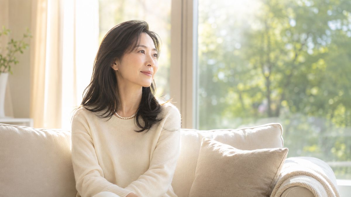 窓辺のソファに座り外を眺める女性