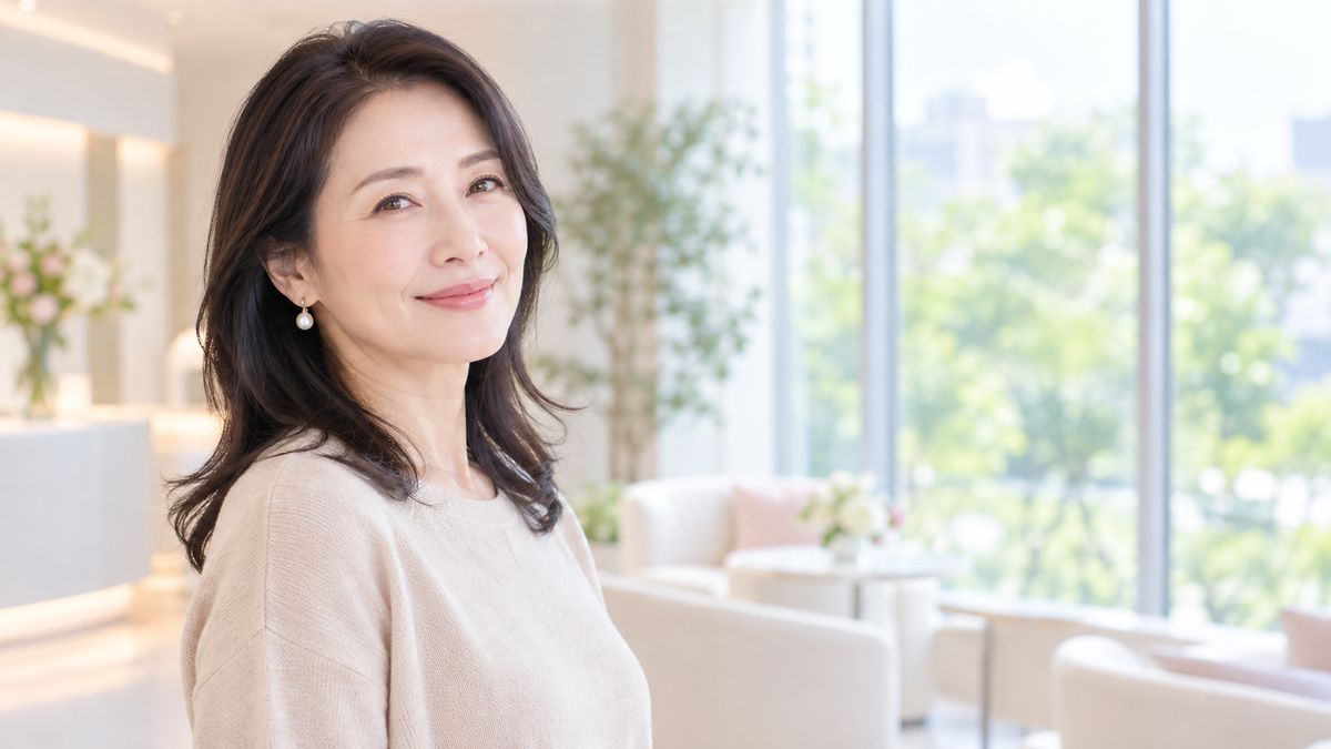 窓際に立ち穏やかな表情で前を向く女性