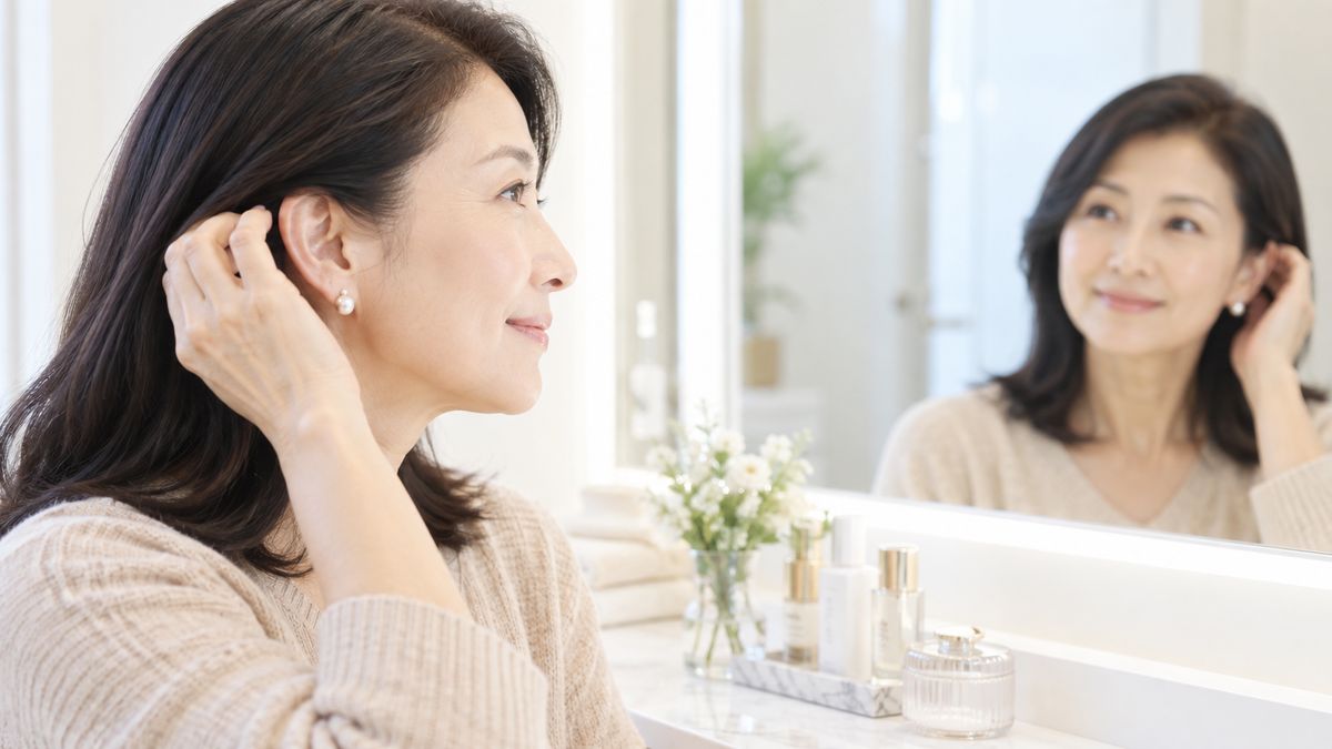 鏡の前で髪を耳にかける女性