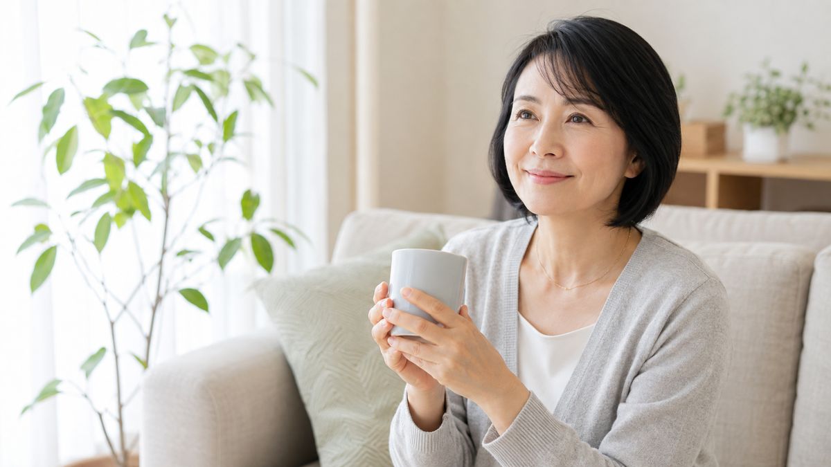 自宅の窓辺でマグカップを持つ女性