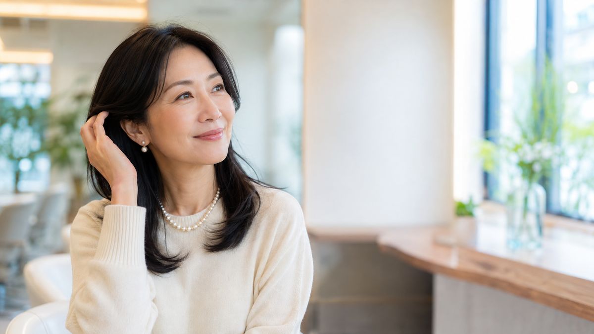 窓際の席で髪を耳にかけて微笑む女性