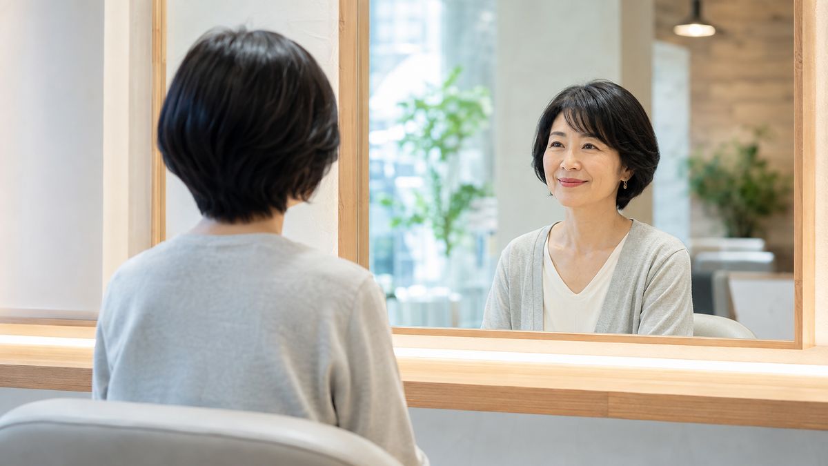 サロンの鏡に向かって座る女性の後ろ姿