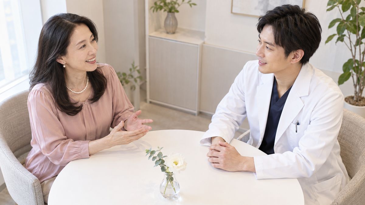 丸テーブルで男性医師に笑顔で話す女性