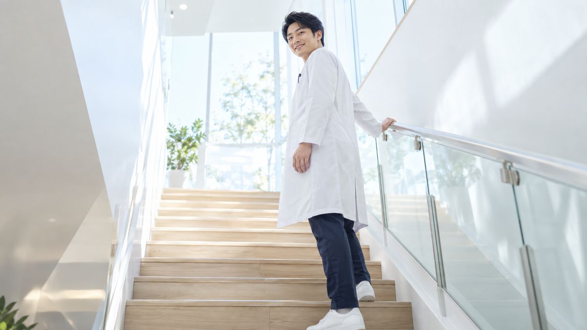 階段の途中で振り返って微笑む白衣の男性医師