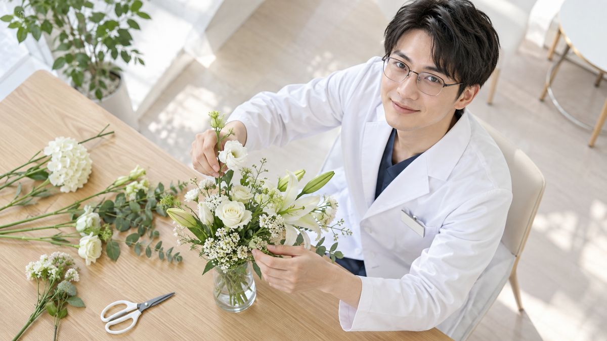 テーブルで白い花を花瓶に生ける眼鏡の男性医師