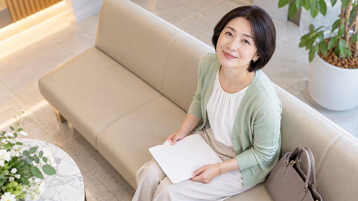待合の長椅子でパンフレットを持つ女性