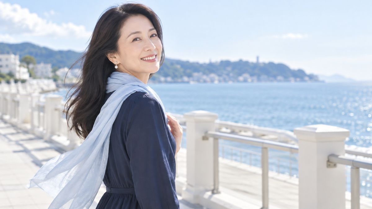 海沿いの遊歩道でストールをなびかせ振り返る女性