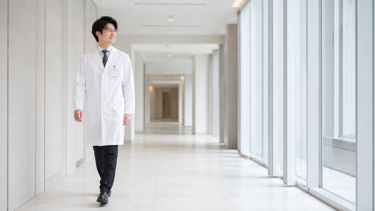 クリニックの廊下を歩く眼鏡の男性医師