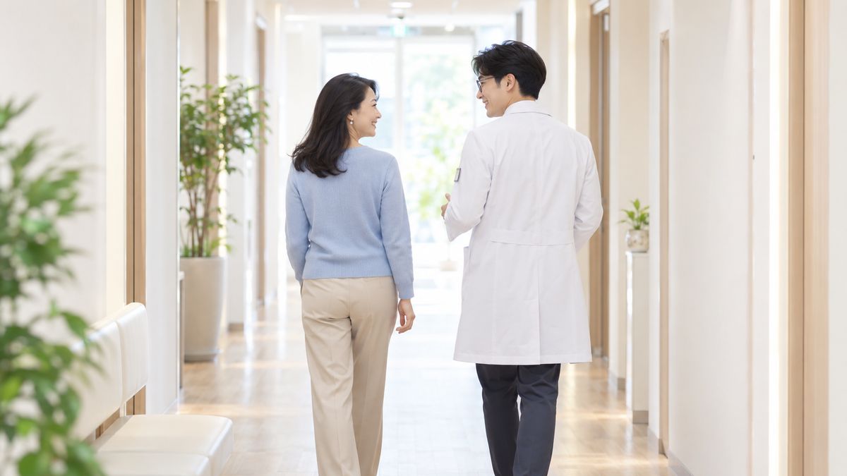 廊下を眼鏡の男性医師と並んで歩く女性の後ろ姿