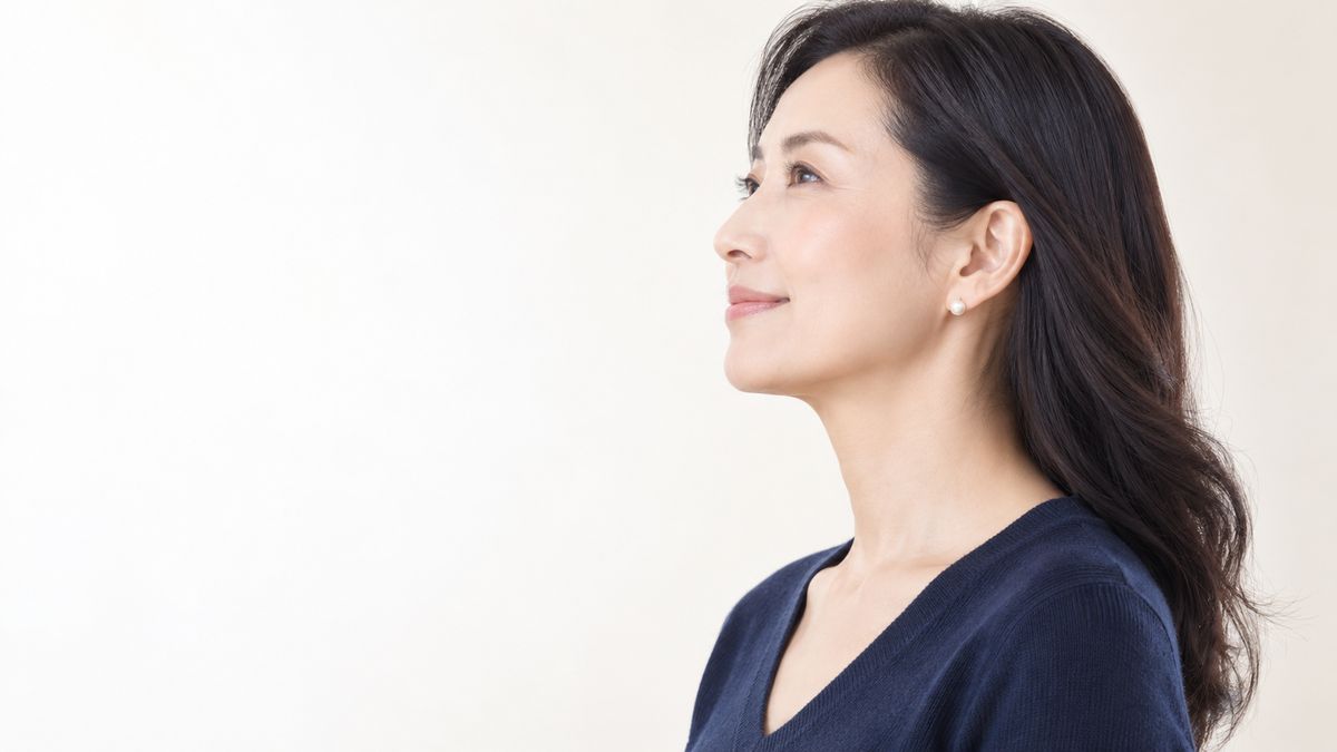 髪を耳にかけて微笑む女性の横顔