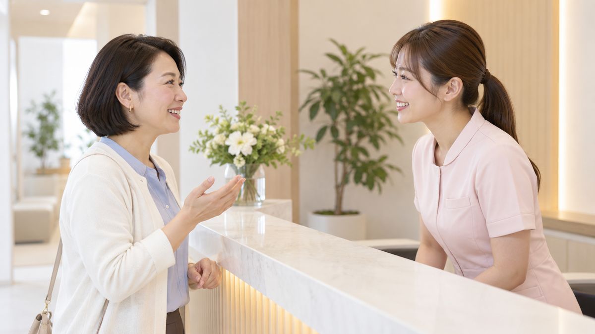 受付カウンターでスタッフに笑顔で質問する女性