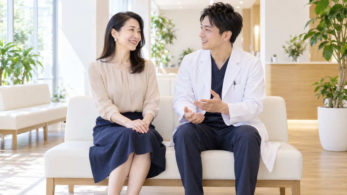 待合スペースのベンチで男性医師と並んで話す女性