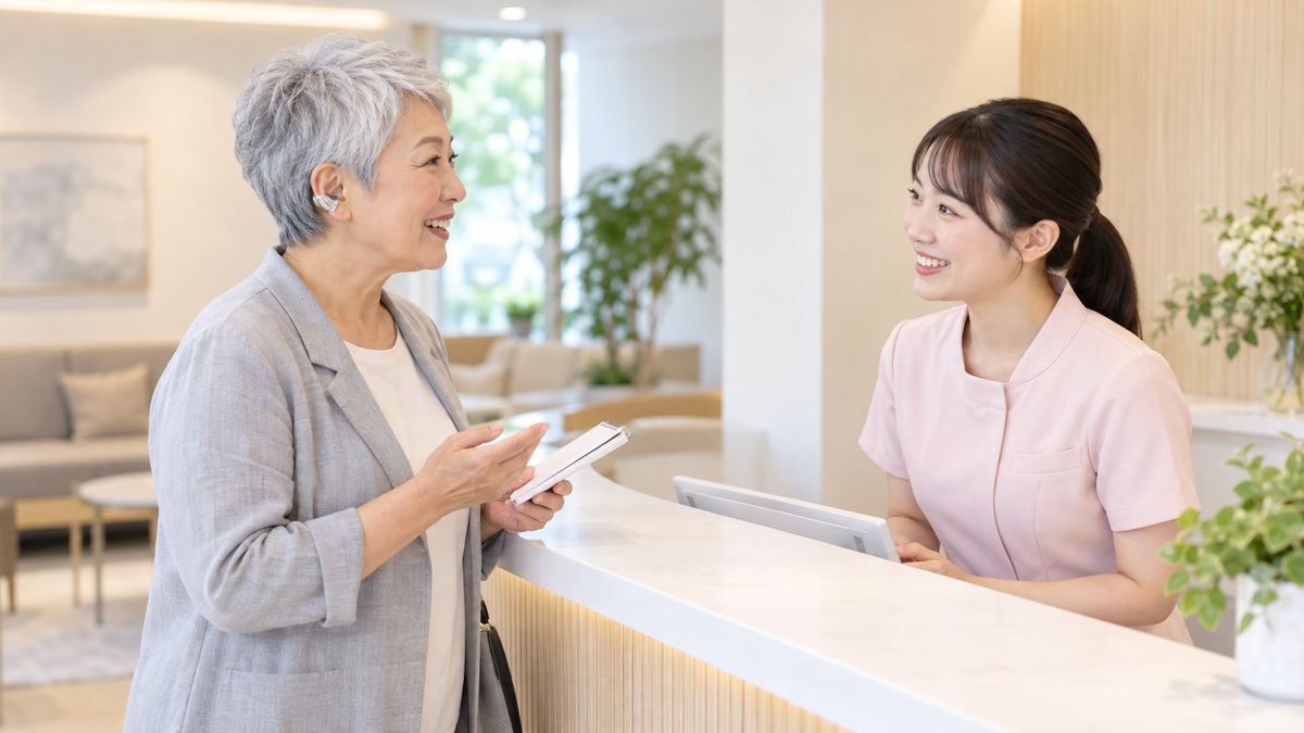受付カウンターでメモを手に質問する女性と笑顔のスタッフ