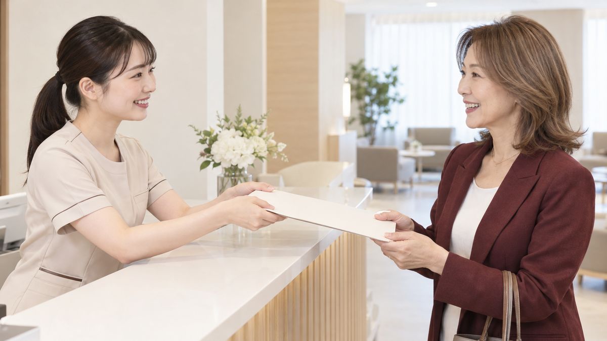 受付カウンターでスタッフからファイルを受け取る女性