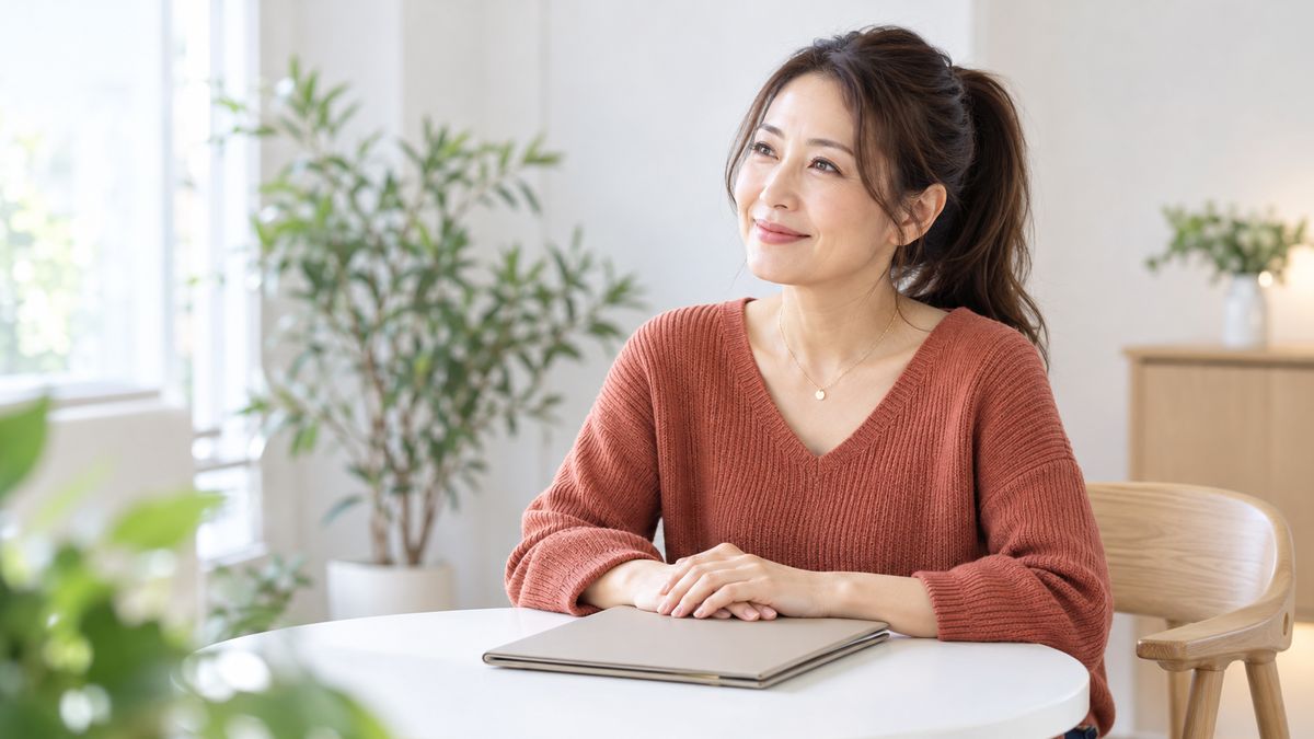 相談室のテーブルでファイルに手を添えて微笑む女性