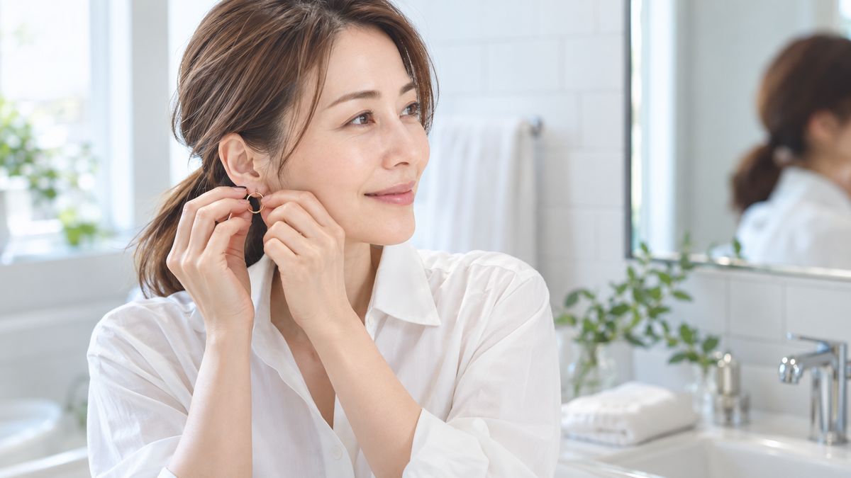 洗面台の前で素顔のままピアスを外す女性