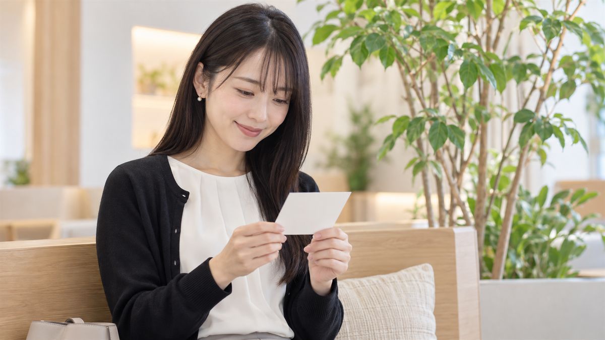 ラウンジのベンチで小さなカードを手に微笑む女性