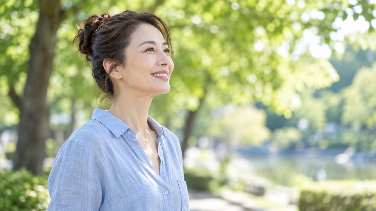 公園の木陰で前を向いて微笑むお団子髪の女性