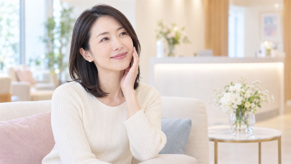 待合のソファで頬に手を添えて微笑む女性