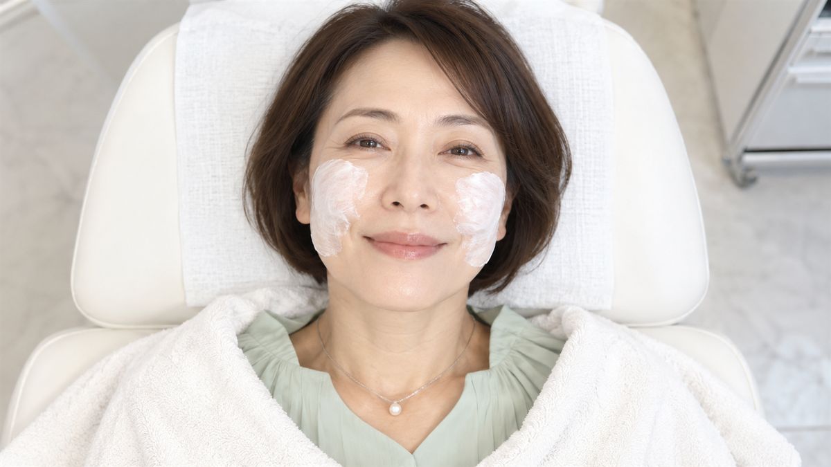 両頬に白いクリームを塗りチェアで目を細める女性